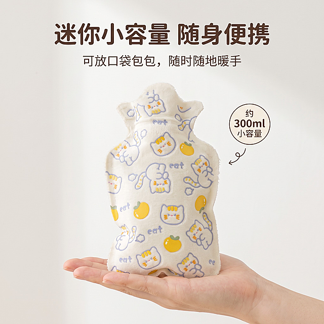 严格还原上传的橘子猫咪款热水袋产品图，包括布套设计、颜色、卡通图案元素等所有细节，产品外观必须与参考图完全一致，不得改变包装设计、配色方案，保持产品的真实材质质感，亲肤植绒面料哑光柔和质感，电商商业主图，精致杂志图文排版，柔和奶油漫射柔光，干净低饱和奶油风背景，全套统一日系软萌治愈风格；所有中文文字统一使用圆润可爱无衬线圆体，文字排版留白充足，文字不遮挡产品主体，层次分明。画面内容：猫咪款迷你热水袋，放置在干净手掌上做尺寸对比，平视角度，奶白色纯色背景；【主标题】画面顶部："迷你小容量 随身便携"，【副标题】主标题下方小字："可放口袋包包，随时随地暖手"；信息布局：手掌 + 热水袋放置画面中下区域，标题文字在上，侧边圆角小字标注："约 300ml 小容量"；设计感强调：柔和自然光，直观对比展示产品大小，简约杂志图文排版，直观易懂。