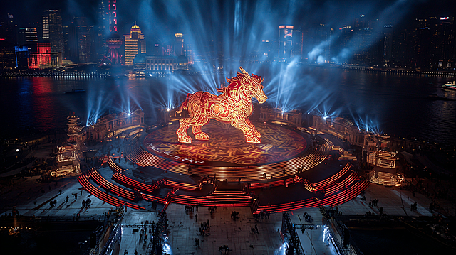 2026 Year of the Horse Spring Festival, Bund International Architecture Complex, giant changes formation with jumping steps, drone aerial shot, giant traditional → digital light array totem, cinematic texture, ultra-realistic rendering, high dynamic range, slight film grain, red and gold main tone with urban cool blue contrast, particle energy effects, Cinematic, epic scale, hyper realistic, Cyber Oriental Aesthetic