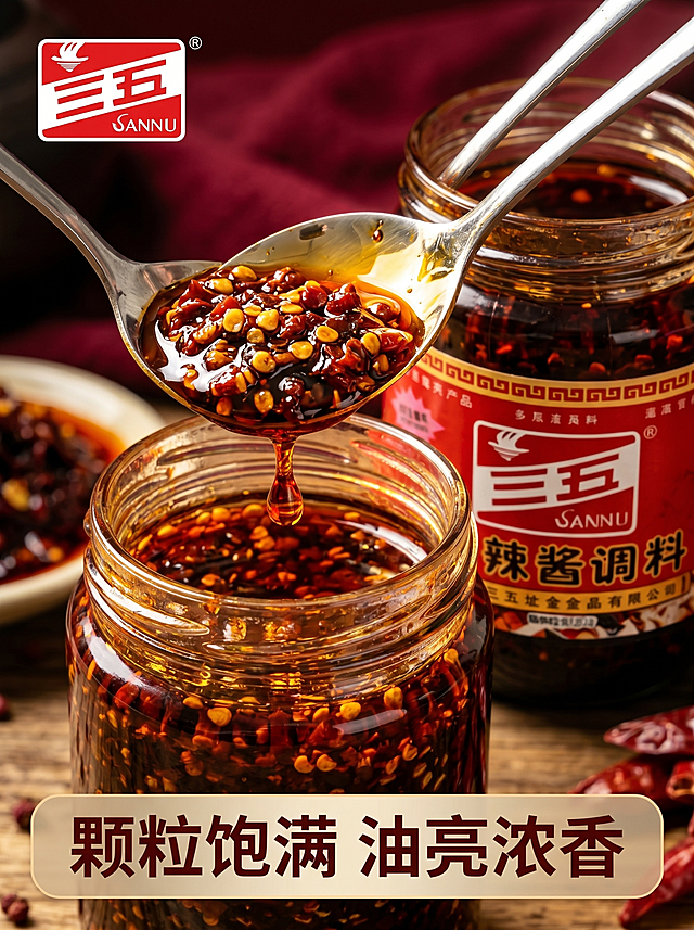 [主图-3] 三五香辣酱微距细节图
[氛围风格] 质感诱人，食欲满满，突出酱料颗粒细节
[画质] 商业摄影质感、光线柔和通透、产品清晰真实、画面干净高级
[元素] 勺子舀起香辣酱悬停在罐子上方，酱料油亮浓稠，辣椒籽和辣椒颗粒分明，红油欲滴的动态瞬间。背景虚化突出酱料质感。保持产品罐子外观与原图一致。商品主体酱料占比约70%，画面满屏无边框。Logo放置左上角。
[光影] 逆光拍摄，光线穿透红油呈现琥珀光泽，油亮反光凸显浓郁质感
[配色] 深红酱色+红油琥珀色，深背景衬托，突出酱料色泽
[视角构图] 特写近景，焦点落在酱料颗粒上，景深较浅突出主体
[文字版式] 画面底部半透明悬浮条，横向排列文字「颗粒饱满 油亮浓香」，浅色字体清晰不抢主体。
[比例分辨率] 3:4 比例，2k 分辨率；文字清晰可辨，超高清
[负向提示词] 变形，水印，文字错乱，产品图模糊，背景杂乱，价格信息。