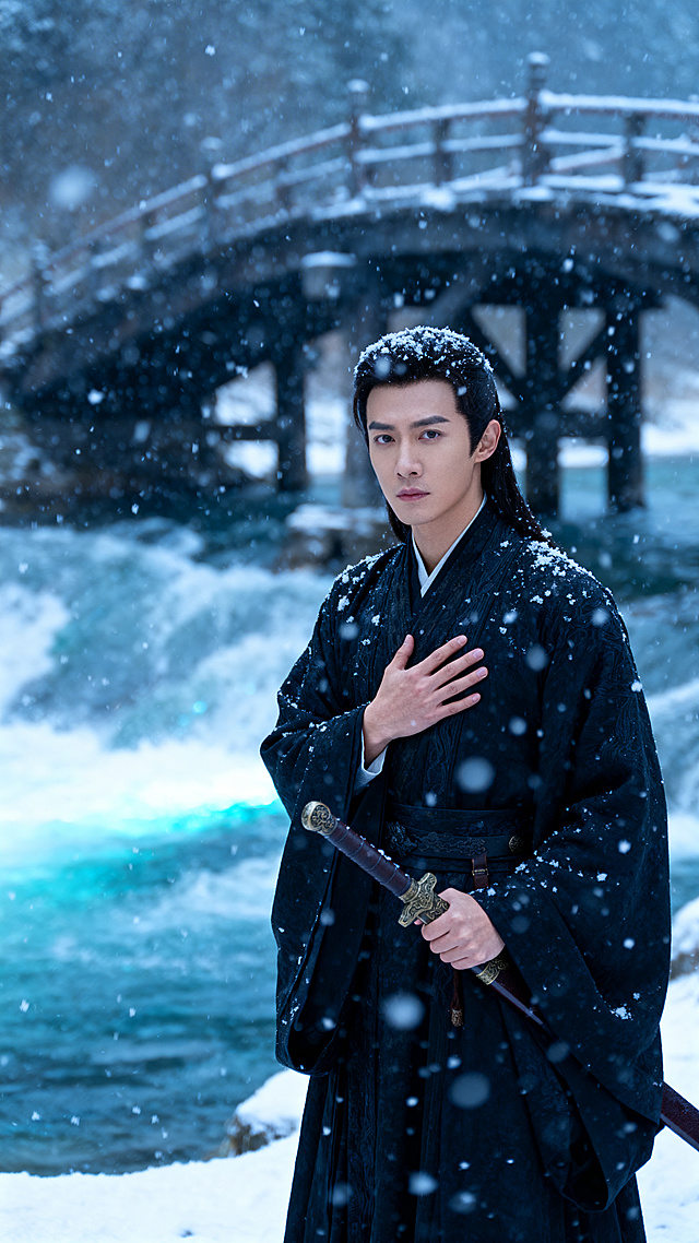 飘雪的天气里，穿玄色剑袍的东亚男子独自站在雪中，手按在胸口握剑，眼神坚定，衣袍上落满了雪花，背景是飞雪的断桥与奔涌的河流，景色壮观，写实电影唯美风格，无违规内容。