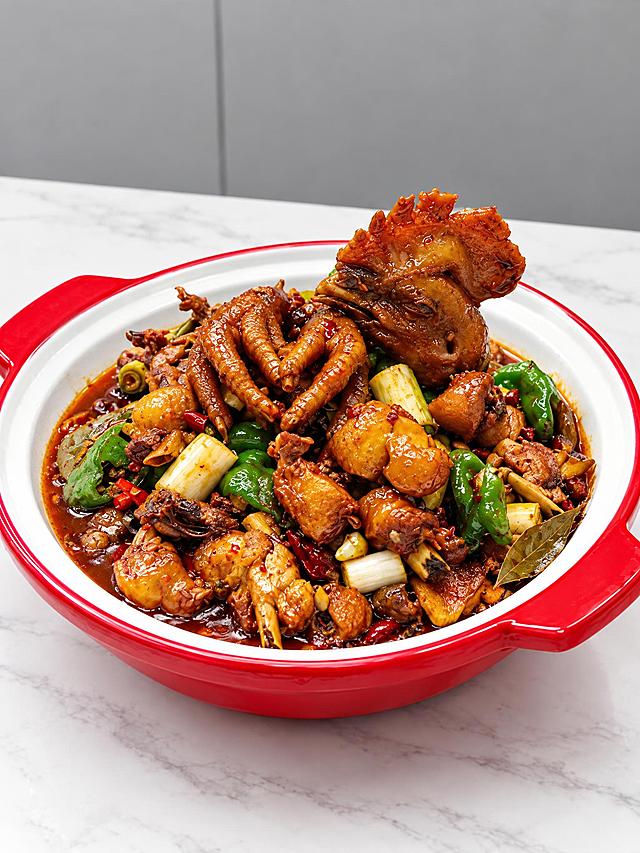 基于参考图中的红烧土鸡菜品，生成右侧45度斜角角度的美食摄影图，保持鸡肉色泽红亮浓郁，带鸡头鸡爪，搭配青椒、葱段、姜片、香叶等配料，红边白瓷双耳锅装盛，白色大理石桌面背景，灰色墙面，专业美食摄影，高清细节，浓郁诱人