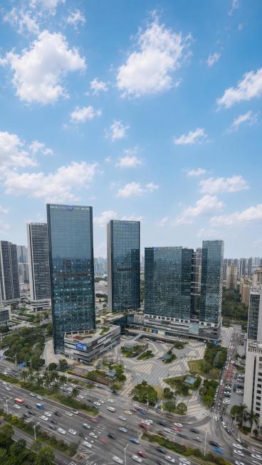 基于原图，加长天空部分，更改图片比例为9:16，添加车水马龙的车流效果，保留原有的建筑群和广场预览效果