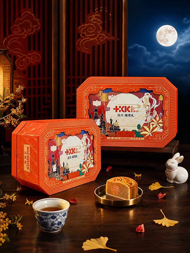 超写实中秋节日食品礼盒场景摄影。
主体：两款中秋坚果月饼礼盒严格参照上传产品图，完整保留所有可见组件、轮廓、结构、比例、材质、颜色与产品本体上的文字信息（logo/品牌名/图案/浮雕等），与上传图完全一致；自然融入场景光影，与场景共处同一物理空间。礼盒为红色八角形包装，正面印有"喜月·璀璨礼""HiKamKee喜锦记"等字样及敦煌飞天、玉兔、城市建筑、圆月等国潮插画图案。
构图：礼盒组合占画面约65%，完整不裁切；一款礼盒正面朝前置于C位略高，另一款礼盒侧面45°朝向左前方略低，错落摆放，两盒之间留有合理物理空间，无穿模重叠；45°微俯视角，中景构图；背景无其他同类食品包装。
风格：新中式轻奢，高大上有格调。
场景：中秋雅致中式茶席场景，夜晚暖光氛围。
空间：①承载面，深胡桃木实木茶桌，木纹细腻温润；②背景，深朱红色中式屏风，隐约可见金色云纹暗花；③右上方，一轮皎洁满月悬于深蓝色夜幕，周围有淡淡祥云。
陈设：①C位，两款红色中秋礼盒（主体），错落摆放；②礼盒前方左侧，一只青花瓷小茶杯，盛半杯琥珀色茶汤；③礼盒前方右侧，一只黄铜色小月饼托，上面放一块切开的莲蓉月饼，断面油润；④茶桌左角，一枝金色桂花枝，花朵细碎点缀；⑤茶桌右角，一只白色陶瓷小玉兔摆件，圆润可爱；⑥礼盒周围散落3-5片金色银杏叶与红色干花瓣。
配色/材质：中国红/深胡桃棕/月白/鎏金/青花瓷蓝；哑光纸质礼盒/实木/陶瓷/黄铜/丝绸/玻璃。
光影：主光从右上方45°斜射，模拟月光与暖灯混合光源，照亮礼盒正面国潮插画细节，红色包装呈现温润哑光质感；辅光为左侧暖黄色环境反射，阴影柔和过渡；礼盒底部有自然投影，茶桌面有微弱环境反光。
氛围：高端礼赠感，中秋佳节团圆意境，温馨雅致，国潮格调。
参数：4K写实光追，商业摄影级质感。严格锁定宽高比为3:4。