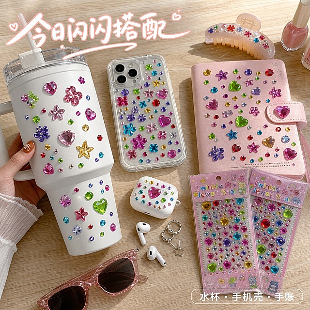 第5张 多场景应用主图｜加州少女DIY桌面
1:1正方形商品主图，加州阳光美式ins风，暖调自然光与补光结合，浅木色桌面，整体松弛明亮，生活化种草感强。
画面桌面随性摆放白色大容量冰霸杯、透明手机壳、粉色手账本、发夹、耳机壳，物件表面均粘贴同款彩色钻石贴纸，贴纸贴合平整，钻面高亮通透，切面反光自然，与包装钻面质感统一，呈现真实DIY效果。画面右下角错落摆放两款原图钻石贴纸包装，作为产品露出，占比适中。桌面点缀银色耳环、粉色甲油瓶、复古墨镜、白色耳机，构图松散随性，像真实桌面分享。可局部露出少女手部拿取水杯，增加真实感。
画面顶部偏左用手写感标题"今日闪闪搭配"，白字浅粉描边；右下角配迷你标签"水杯·手机壳·手账"，透明底白字，融入场景不突兀。