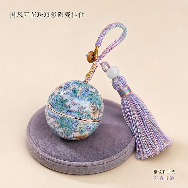 [主图-1] 国风万花款珐琅彩陶瓷分装罐钥匙扣挂件 首图产品展示 突出完整外观与精致质感。
[统一基调] 国风雅致高级风格，整体柔光箱打光，浅米杏色纯色背景，色系统一为莫兰迪紫蓝绿低饱和配色，标题字色为深墨绿，辅助字色为灰紫色，字体采用纤细宋体风格，整体克制精致，无厚重色块。
[画面] 产品完整居中展示，主体占比约70%，球形陶瓷分装罐正面展示完整万花珐琅花纹，罐身描金线条清晰，渐变紫蓝粉流苏自然垂落在一侧，编织挂绳与木珠细节完整。产品下方放置一个同色系的圆形绒布小垫作为衬托，营造雅致质感。产品角度为微俯视45度，罐身旋转开合的中缝描金清晰可见，流苏穗根的白玉珠通透有光泽。
[光影质感] 商业珠宝级柔光摄影质感，主光从左上45度打下，罐身陶瓷面有柔和高光，珐琅彩花纹色彩通透，描金边缘有窄条轮廓光，流苏丝线根根分明有丝绒光泽，产品底部有自然柔和的接触阴影，无硬阴影。
[配色] 背景主色浅米杏色，与产品花纹的紫蓝绿色调呼应，整体色调统一柔和。
[文字版式] 左上角放置纤细宋体主标题「国风万花珐琅彩陶瓷挂件」，字号适中不抢主体；右下角小字辅助文案「雅致伴手礼 随身收纳」，字色深墨绿与灰紫色搭配，文字放在负空间不遮挡产品。
[输出要求] 1:1正方形比例，2K高清，产品清晰锐利，花纹细节完整，文字清晰可读，无变形、错字、模糊、杂乱背景、水印、平台Logo。