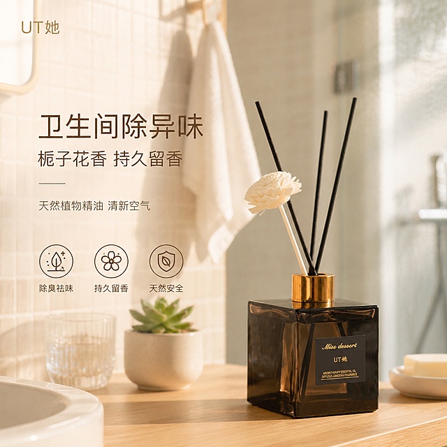 [单张主图] UT她栀子花香薰精油 高级氛围感主图 卫生间除异味场景 更换卫生间背景。
[画面主体] 产品为方形茶色玻璃瓶身无火香薰，金色金属瓶盖，黑色藤条+白色干花藤条，瓶身正面有黑色标签印有金色Miss dessert UT她英文字样。产品置于画面中偏右位置，占画面约50%，正面45°斜侧视角，完整不裁切。保持产品外观（物理结构、材质质感、颜色、标签文字、藤条干花形态）与输入产品图完全一致，杜绝任何变形和色差，精细化处理瓶身玻璃通透感与金色瓶盖金属反光。
[构图版式] 真实使用场景型版式。左侧大面积留白放主标题与副文案，底部3个线稿图标卖点；产品置于右侧真实卫生间台面上，自然融入环境。
[场景元素] 背景为全新的明亮温馨日式风格卫生间场景，浅木色洗手台柜，白色陶瓷洗手盆边缘，墙面是浅米色小方砖，旁边挂着白色毛巾，台面上有透明玻璃漱口杯、一小盆绿色多肉植物、白色肥皂碟作为装饰道具，背景虚化可见磨砂玻璃淋浴区轮廓，空气中有淡淡的柔雾感与阳光斜射的光束，营造温暖舒适的卫浴氛围。产品平稳放置在浅木色台面上，底部有自然投影，无悬浮感。
[文案版式] 左上角安全区放品牌名UT她 金色细体字。左侧中部主标题两行：第一行大号字「卫生间除异味」，第二行稍小「栀子花香 持久留香」。主标题下方副文案一行小字「天然植物精油 清新空气」。底部横向排列3个圆形线稿图标+短词，从左到右：除臭祛味、持久留香、天然安全。所有文字均为深棕色，字体为现代轻无衬线，字重克制，主标题最大，副文案约为标题的1/2大小，图标文字最小。文字全部放在左侧与底部负空间，绝对不遮挡产品主体与瓶身标签。
[光影质感] 主光来自右上方自然窗光，暖金色柔和漫射，光线通透温暖；辅光来自左侧补光，弱化阴影。瓶身茶色玻璃有柔和高光与环境折射，金色瓶盖有清晰金属反光，藤条与干花质感自然。产品底部有柔和接触阴影，与木质台面融为一体。背景浅景深虚化，突出产品主体。整体光影温暖明亮，有午后阳光洒入卫生间的舒适感。
[配色字体] 主色调为浅木色+米白+暖棕（取自卫生间与产品茶色瓶身）；辅助色为金色（取自瓶盖与品牌色）+ 白色（洁具与毛巾）+ 浅绿（植物点缀）。字体为现代轻无衬线体，字重偏细，靠留白与字号对比分层级。
[比例分辨率] 1:1比例，2K分辨率，文字清晰可辨，超高清商业摄影质感。
[负向提示词] 变形，文字错乱，产品模糊，背景杂乱，水印，电商平台Logo，多余的手，畸形手，肢体穿模，人物面部扭曲，产品边缘硬切，悬浮感，原图白底光影残留。