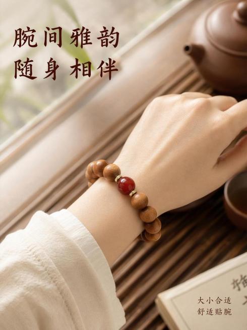 [第6屏] 佩戴展示页-呈现手串上手佩戴效果。
[氛围/风格] 自然生活化场景，温润氛围感，真实佩戴体验展示
[元素布局] 展示亚洲女性手腕佩戴南红映檀款手串【图2】的特写，手腕自然放置在木质茶盘上，预览效果