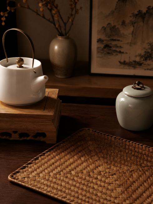 茶具，严格参照上传产品图，完整保留所有可见组件、部件、轮廓形状、结构、比例、材质质感、颜色与上传图完全一致。
室内中式茶桌一角，新中式温馨暖棕色调。
侧逆光（还原参考图主光方向），产品受光面泛起暖棕木预览效果