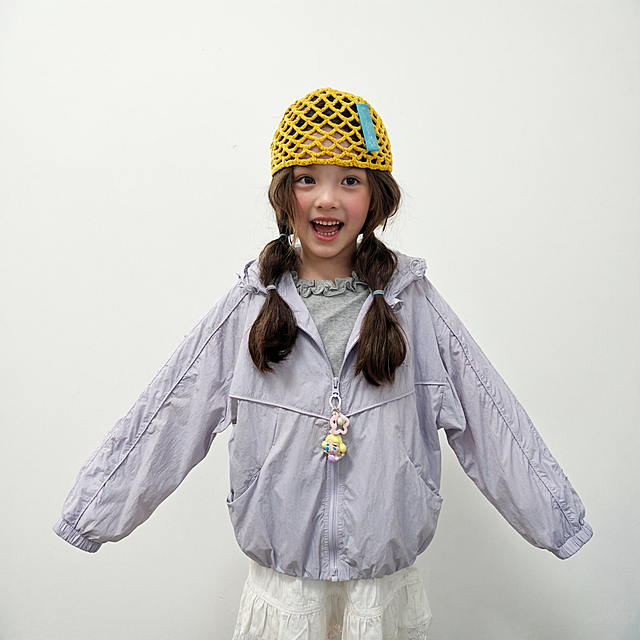 把第二张图中的浅紫色连帽外套穿到图一的小女孩模特身上，将衣服的拉链完全拉上，保持衣服原有的质感和浅紫色，保留小女孩原本的姿势、背景和其他穿着，自然合身