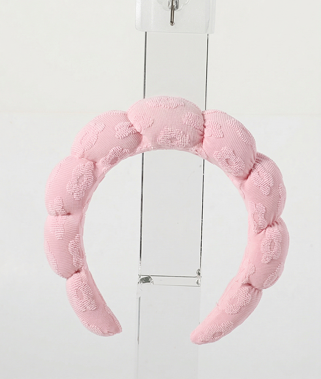 去除图片中间的吊卡，补全被吊卡遮挡的粉色发箍部分，保持发箍的花纹和材质一致，保留透明展示架和纯白背景，整体风格和原图保持一致