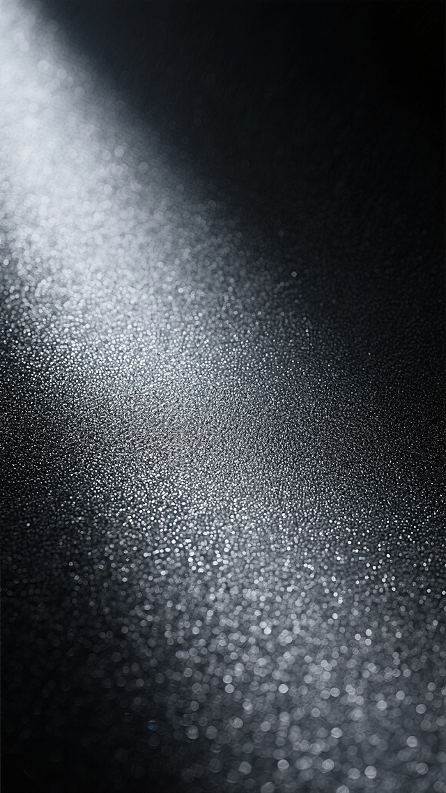 一张具有深邃黑色调的金属纹理背景，表面呈现出细腻且均匀分布的磨砂质感，颗粒感清晰可见，整体散发着冷峻、工业风的氛围。光线从左上角以柔和的角度照射，在纹理表面形成微妙的明暗对比，增强了金属的材质立体感，无任何文字、logo或图案干扰，仅专注于展现纯粹的金属磨砂肌理。