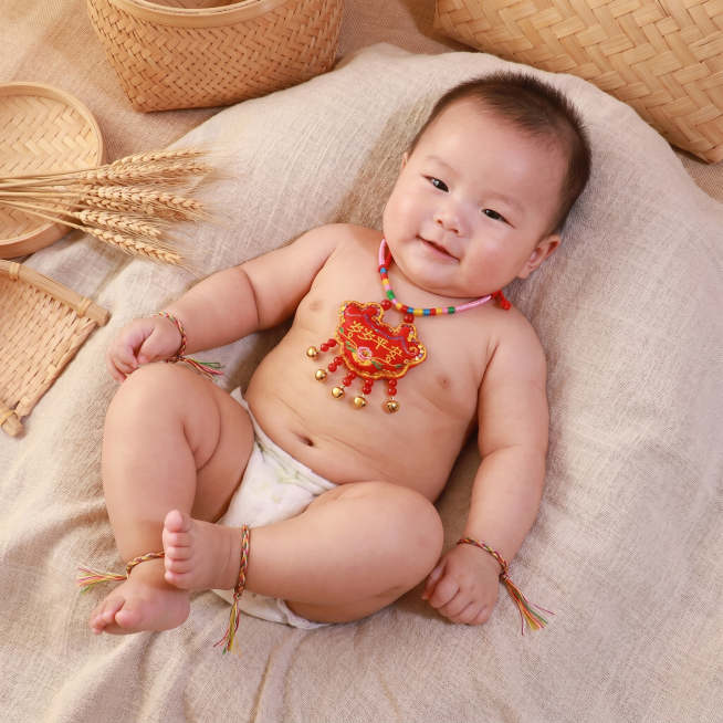 生成1张百天婴儿图，婴儿脖子上戴着图中的岁岁平安项圈香包，手腕和脚腕上都戴着图中的五彩绳，风格自然预览效果