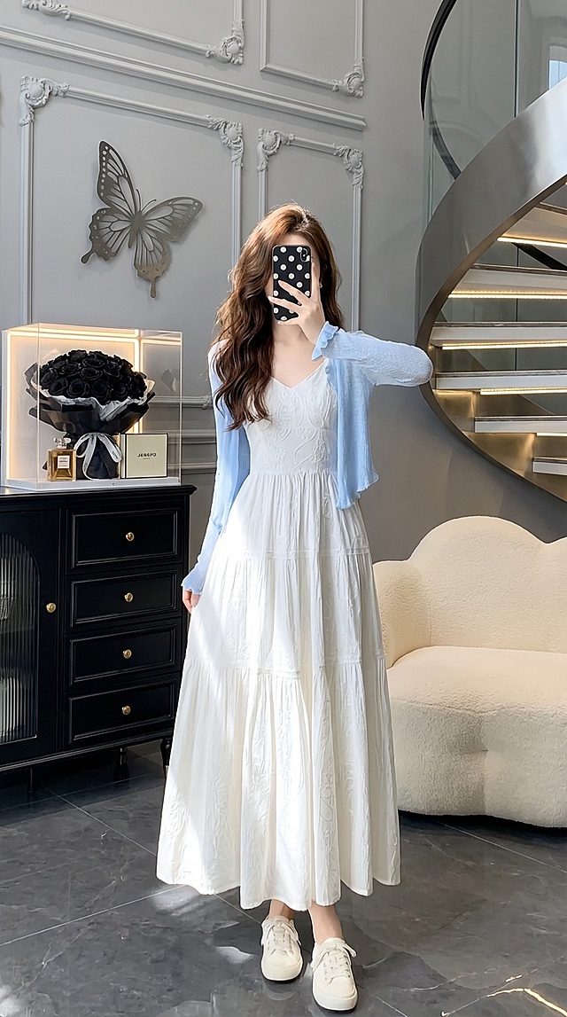 消除原背景，帮我更改为人物穿着和图片一样的衣服。穿白色休闲鞋。人物手拿手机挡脸自拍（面部全部挡住），手机壳改为(黑色波点)，发型(棕色柔顺波浪长发，左边披肩，右慵懒在肩后)，墙面浅灰色基底加立体石膏造型加金属做的镂空大蝴蝶，地面是深灰色釉面砖，人物左侧是半张黑色带金色金属抽屉欧式柜子(摆放带有灯光的大大大大的透明展示盒，展示盒内有黑色玫瑰花束，柜子上还有香奈儿香水瓶，Iv盒子，)，右边有半张奶白色云朵形慵懒羊毛沙发，右侧是匹配以上场景的旋转楼梯配玻璃扶手楼梯台阶有灯带，强烈要求(人物在柜子与楼梯之间，人物与柜子和楼梯不重叠，沙发和楼梯不重叠)衣服细节不变，颜色不变，款式不变形，比例9:16，有柔和灯光在模特头发和衣服上，整体光线柔和自然，照片为 8K 分辨率，超细节，柔焦效果，整体搭配有高级质感!生成4张。，