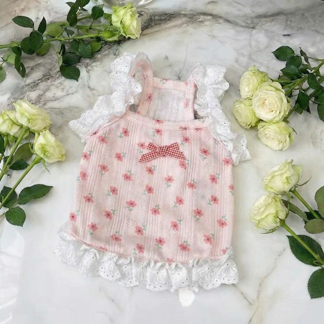 保留图片中粉色碎花宠物衣服的所有细节，包括红白格子蝴蝶结、白色蕾丝木耳花边、粉红花纹和竖条纹纹理，更换大理石背景和绿色花朵摆位，重新生成一张原创的平铺宠物衣服商品图，高清质感，自然光影预览效果