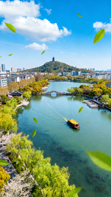 白天南通濠河俯视图，河中有游船，远景是狼山，蓝天白云，春意盎然，河面上飘着绿叶，场景唯美动人预览效果