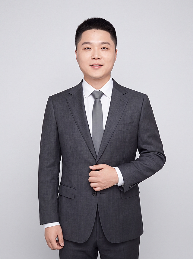参考图中人物的脸型、发型、五官特征保持不变，生成年轻清爽的90后职场精英形象照。标准焦段50mm，f/4光圈，平视视角，镜头与人物视线齐平。人物占画面70%，居中构图，位于画面中心为视觉聚焦点，半身照，左右留少量背景空间，头部与画面顶部保留5%空间，头肩比例协调，人物结构准确。身穿深灰色高级挺阔西装外套，平驳领设计，面料为高支羊毛混纺，质感硬挺有型，剪裁利落修身，肩线挺拔；内搭纯白色高支棉衬衫，干净利落，系深灰色哑光窄版领带；下装深灰色同面料西裤；着装简洁高级，年轻精英气质，身形匀称挺拔。呈自然站姿，右手轻搭西装翻领，左手自然下垂，肢体放松自信。发型干净利落，精神清爽。脸部紧致瘦脸，下颌线清晰，脸部线条利落，肤色白皙透亮，去黄气，皮肤干净清透，呈现年轻健康的白皙肤色。浅灰色纯净背景，均匀柔和，极简干净，背景光线均匀明亮。画质超高分辨率、细节清晰，现代清爽高级感风格。肤质精细化处理，眼神明亮有神，直视镜头，表情自然带淡淡微笑。皮肤白皙细腻，通透有光泽，零黄气，哑光清透肤质，保留真实皮肤纹理但更显年轻。杰作，最佳画质，超高细节，写实摄影，中近景人像，皮肤质感清透白皙，明亮柔光，正面均匀补光，画面干净明亮，高清皮肤细节。面部光比1:1，5200K冷白光，脸部紧致提升，下颌线清晰，脸型更立体小巧，肤质清透白皙，面部柔光，轻透裸妆感，真实毛孔纹理但更细腻。去除所有配饰。