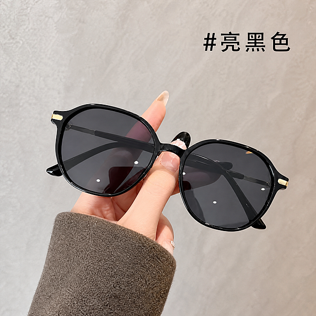 [单张主图] 亮黑色墨镜，高级氛围感主图，复刻参考图的构图和版式，更换掉原商品图中的人手，保持墨镜的整体位置和构图不变。参考图布局为：浅灰色纹理背景，墨镜被手托举在画面中央偏左位置，右上角标注颜色文字。保持墨镜亮黑色外观（亮黑色镜框、深灰色镜片、金色装饰细节）与输入产品图完全一致，杜绝任何变形和色差，精细化处理。商品主体占比严格控制在60%-70%之间，画面满屏无边框。右上角保留文字"#亮黑色"，文字版式和颜色参考参考图设计。光影：主光为柔和均匀的室内自然光，清晰勾勒墨镜轮廓和亮黑色镜框的质感，镜片有自然通透光泽，细节处光影层次分明，背景光线均匀干净。配色：主色调为浅灰色背景，搭配墨镜亮黑色，金色点缀，整体配色简约高级，保持与参考图一致的视觉风格。比例分辨率：1:1比例，2k分辨率，文字清晰可辨，超高清。负向提示词：变形，水印，文字错乱，产品图模糊，背景杂乱，人手变形，结构错误