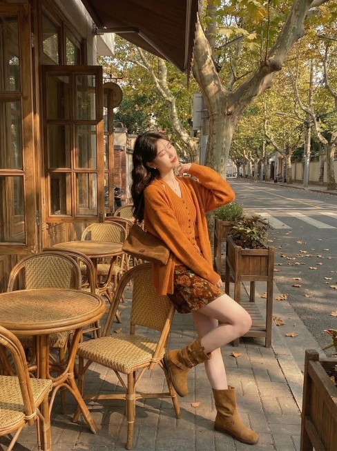 保留这套焦糖色系秋日穿搭，模特改为坐在藤椅上轻轻歪头搭手靠背姿势，复古咖啡馆梧桐露台午后暖金色阳光，凸显整体穿搭版型和细节质感，抖音带货风格，慵懒松弛预览效果