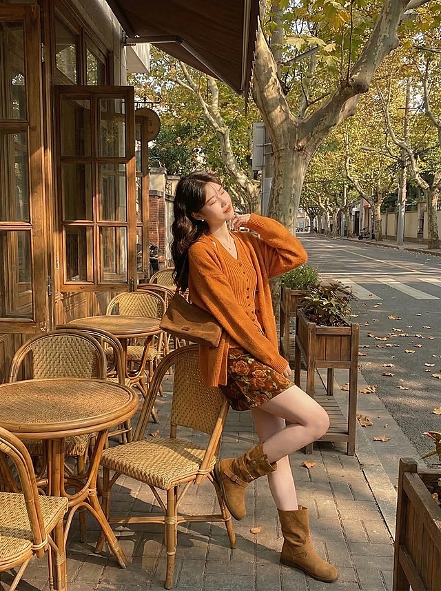 保留这套焦糖色系秋日穿搭，模特改为坐在藤椅上轻轻歪头搭手靠背姿势，复古咖啡馆梧桐露台午后暖金色阳光，凸显整体穿搭版型和细节质感，抖音带货风格，慵懒松弛