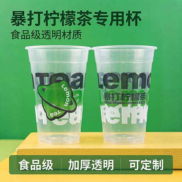 [主图-1] 暴打柠檬茶一次性透明塑料杯产品首图。
[氛围风格] 清新自然茶饮店氛围，干净清爽。
[画质] 商业摄影质感、光线柔和通透、产品清晰真实、画面干净高级。
[元素] 两个暴打柠檬茶透明塑料杯居中放置在浅原木色黄色台面上，绿色纯净背景，顶部预留出文案放置空间。保持杯子外观、物理结构、材质质感、颜色与输入产品图绝对一致，杜绝任何变形和色差，精细化处理。商品主体占比严格控制在65%左右，画面满屏无边框。
[光影] 正面柔和均匀棚拍光，透明杯体通透感清晰体现，背景光影干净无杂，杯底阴影自然过渡，整体高亮通透。
[配色] 主色调为清新绿色背景搭配原木黄色台面，与杯子上绿色图案配色呼应，整体和谐醒目。
[视角构图] 平视中心构图，画面简洁主体突出，景深适中。
[文字版式] 左上负空间左对齐留安全边距，大字主文案“暴打柠檬茶专用杯”，深绿色粗体无衬线字体最大号；辅助文案“食品级透明材质”约半高同色系。底部通栏均分三列，列内左对齐，文案为「食品级」「加厚透明」「可定制」，白字深绿色半透明底，对比清晰。
[输出要求] 1:1比例，文字清晰可辨，超高清商业摄影质感。
[负向提示词] 变形，文字错乱，产品图模糊，背景杂乱，水印，电商平台Logo。