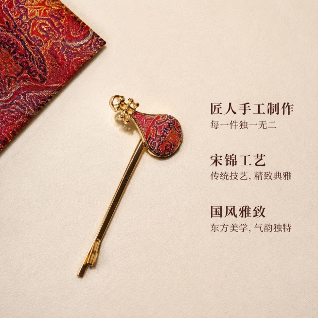 [主图-5] 整体卖点展示，呈现产品独一无二手工价值
[氛围风格] 简约国风陈列，整体精致高级
[画质] 商业摄影，干净清晰，质感统一
[元素] 本款漳州宋锦葫芦琵琶一字夹放置在浅米色绒布上，居中展示预览效果