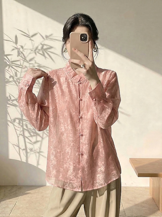 保持人物姿势、身材比例、脸型发型、暖色系新中式极简背景不变，仅将人物身上的金色衬衫替换为图片中的粉色提花新中式衬衫，保留这件粉色衬衫的所有细节：立领、粉色盘扣、提花纹理、通透的纱质面料和 original 版型，适配人物身体自然呈现穿着效果，光影和风格与原图保持一致，服装自然贴合身体，不改变人物整体结构和背景氛围。负向提示词：服装变形、细节丢失、颜色不对、纹理错误、比例失调、人物扭曲、水印、文字