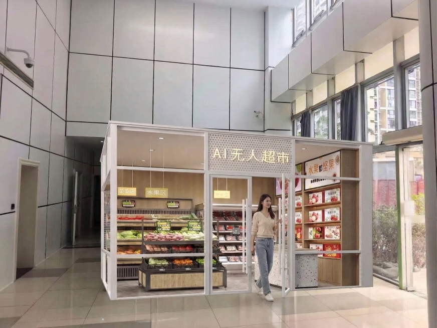 保留图中AI无人超市的所有内容、大小、风格完全不变，仅将超市门口的女生修改为正推开玻璃门从超市里面走出来的状态，女生外貌、穿着和原图完全一致，动作自然，光线与整体风格融合预览效果