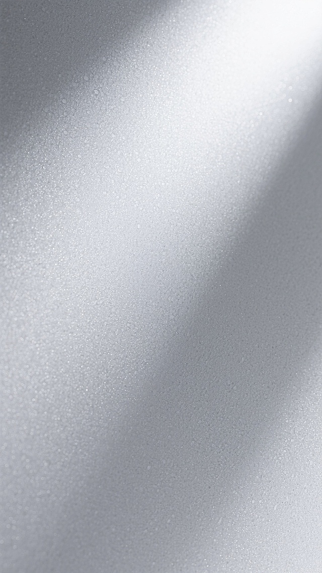 磨砂质感的灰色背景，表面带有细腻均匀的颗粒纹理，整体呈现出柔和的哑光光泽，光线从右上角斜射形成自然的明暗过渡，色调以浅灰到深灰的渐变为主，营造出简约、现代且具有高级质感的视觉效果，无任何文字或图案元素干扰。