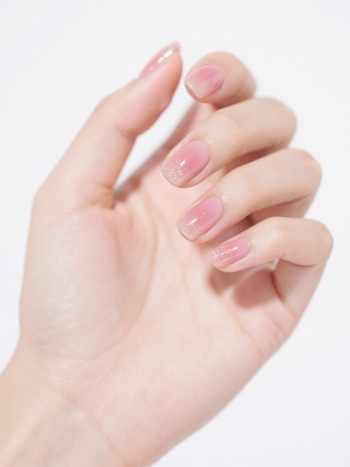 一只女性的手，手型自然舒展，手指微微弯曲，掌心朝向内侧，指尖微微上扬，保持纯白色背景，指甲修剪为圆润的方形甲，甲面光滑饱满，涂有带有细闪的蜜桃粉色渐变美甲，美甲表面有镜面般的高光反射，边缘线条清晰，整体呈现出细腻的皮肤质感和精致的美甲光泽。预览效果