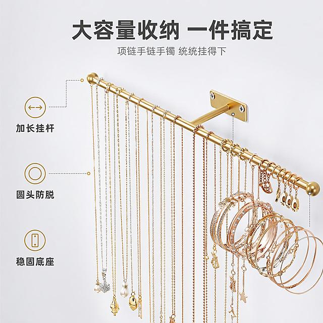 [主图-2] 金色壁挂首饰收纳挂架大容量结构展示图
[氛围风格] 简约功能展示风，突出收纳容量与结构设计
[画质] 商业摄影质感、光线均匀明亮、产品细节清晰、画面干净整洁
[元素] 金色壁挂首饰收纳挂架45度斜侧视角，挂架上满满当当悬挂各种首饰：左侧密集悬挂多条长短不一的项链，右侧挂有多款手镯手链和戒指挂饰，展示大容量收纳能力。背景为纯净浅灰色渐变，突出产品结构。画面左侧用引线标注三个结构亮点：挂杆长度、圆头防脱设计、壁挂底座。保持金色壁挂首饰收纳挂架外观（即物理结构、材质质感、颜色）与输入产品图绝对一致，杜绝任何变形和色差，精细化处理。商品主体占比约65%。
[光影] 顶部柔光箱均匀打光，左右两侧补光，金属材质呈现细腻光泽和高光边缘，无明显阴影，产品立体感强。
[配色] 主色调暖金色+浅灰色，辅助色白色，简洁专业。
[视角构图] 45度斜侧俯视视角，产品从左上延伸至右下，对角线构图增加动感，左侧预留文字和标注空间。
[文字版式] 顶部居中大字主文案"大容量收纳 一件搞定"，深灰色粗体无衬线；下方小字"项链手链手镯 统统挂得下"，浅灰色。左侧三个标注点配短句："加长挂杆""圆头防脱""稳固底座"，金色图标+深灰文字，引线清晰不杂乱。
[输出要求] 1:1比例，文字清晰可辨，超高清商业摄影质感
[负向提示词] 变形，文字错乱，产品图模糊，背景杂乱，水印，电商平台Logo