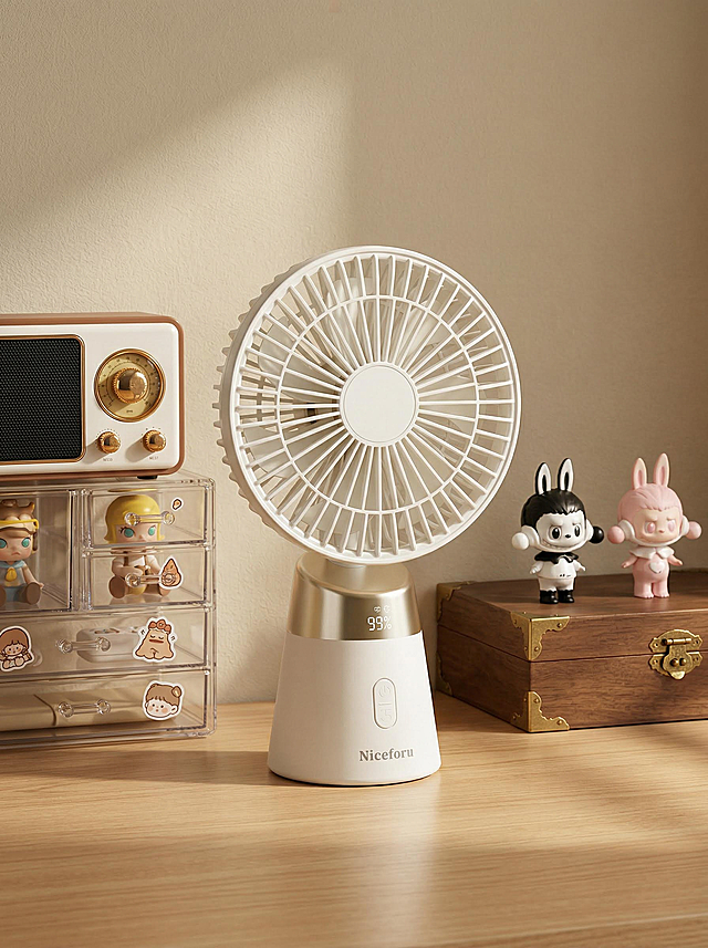 现代复古中古风家居桌面风扇商业摄影，暖调柔和侧逆光，45°侧前方平视偏俯视角，中心构图，一点透视。画面主体为原木色哑光实木桌面，纹理细腻清晰，表面为哑光清漆质感，无明显反光。桌面视觉中心放置图1中的桌面风扇。风扇左侧靠墙是猫王小王子复古收音机，机身主体为奶白色与浅棕色塑料材质，正面有金色金属旋钮与黑色喇叭网罩；收音机放置在四层亮两格透明亚克力收纳盒，盒内摆放不同的迷你泡泡玛特手办与贴纸。风扇右侧靠墙是扁平复古风格木质收纳箱，箱体为深棕色实木材质，表面有金色金属包边与锁扣，箱盖上摆放两个泡泡玛特卡通手办，一个为黑白调，一个为浅粉色调。背景为米色哑光乳胶漆墙面，暖调阳光在桌面投射出柔和的斜向光影，光影过渡自然。整体配色以奶白色、浅原木色、浅米色为主，辅以浅棕色、深棕色、金色点缀，低饱和度暖调复古色系，营造出温馨治愈的桌面氛围感。相机参数为50mm定焦微距镜头，f/2.8大光圈，ISO100，快门1/125s，焦平面精准落在风扇主体，背景轻度虚化，浅景深效果，超高清细节，真实还原塑料哑光质感、实木纹理、亚克力通透感与金属高光，画面干净通透。