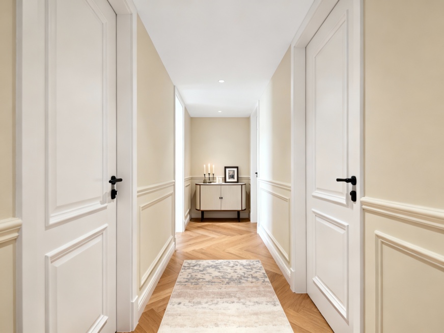 现代简约 + 轻法式风格的住宅玄关走廊，整体氛围明亮温馨，细节精致又实用：露出白色平坦天花板，
色调与材质：以浅奶油色墙面 + 白色门 / 护墙板为主，搭配暖调木地板，柔和又显空间通透；
设计细节：预览效果
