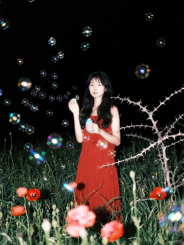 夜晚的荆棘草丛，有红色花朵，女生拿着泡泡玩具（红色长裙），环绕无数动态发光的泡泡。全景，看镜头。