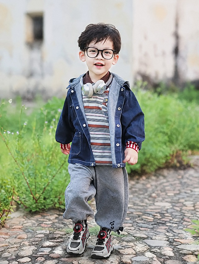 将图中小孩脚上的鞋子替换为图二的黑红灰拼色儿童运动鞋（带旋转纽扣、网面设计、厚底户外款式），保持人物姿态、场景、光线、构图和其余所有元素完全不变，鞋子的角度、透视、光影与脚部和整体画面自然融合，真实自然，无违和感