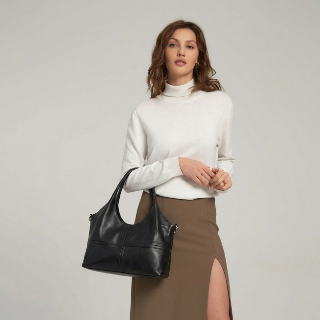 保持模特的姿势、发型、妆容、服装（白色高领毛衣+卡其色开叉半身裙）和浅灰色纯色背景不变，将模特手臂上挎的包替换为参考图中的黑色软皮手提包，包的样式和细节与提供的包包图完全一致，整体画面自然协调，为商业预览效果
