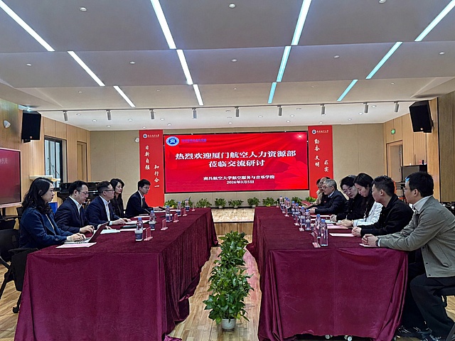 仅修改图中红色大屏幕上的主标题文字，将“热烈欢迎厦门航空有限公司领导一行莅临指导交流”改为“热烈欢迎厦门航空人力资源部莅临交流研讨”。严格保持屏幕的红色背景、字体样式、字号大小、排版位置、透视角度与原图完全一致。所有人物的脸部、五官、表情、发型必须完全保留原样，不得有任何改变。其余场景、桌椅、灯光、装饰、水瓶、植物、两侧竖幅文字、屏幕下方的学院名称和日期文字等所有元素均保持不变，整体画面自然真实，无修改痕迹