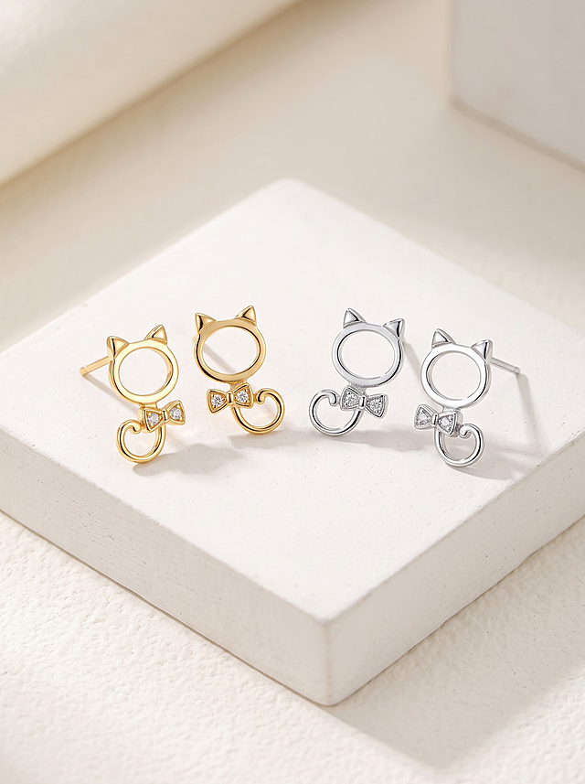 将图中的猫咪造型耳钉产品放置在米白色方形石膏展台上，画面中包含一对亮金色耳钉和一对亮银色耳钉（共四只，款式完全相同仅颜色不同），背景为简约饰品静物拍摄风格的奶白色立体光影背景，米白色调，柔和自然光。产品保持原有细节不变，没有耳堵，耳针样式不变，金属质感真实细腻，钻石闪耀，高级珠宝摄影质感，产品真实化