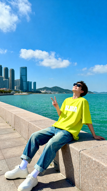 主体人物上身是一件亮黄色oversize短袖T恤，印有白色的字母图案，下身搭配水洗蓝直筒牛仔裤，裤脚做了卷边处理，脚上穿厚底小白鞋配白袜子。人物坐在岸边石台上，身体微微后仰，一只手撑在身侧，另一只手比预览效果