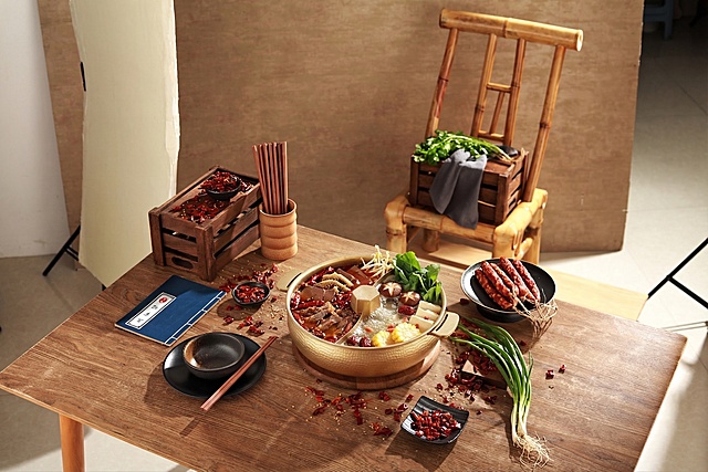 在鸳鸯火锅中添加火锅食材，保留原有的桌子、餐具、布置和整体构图风格不变