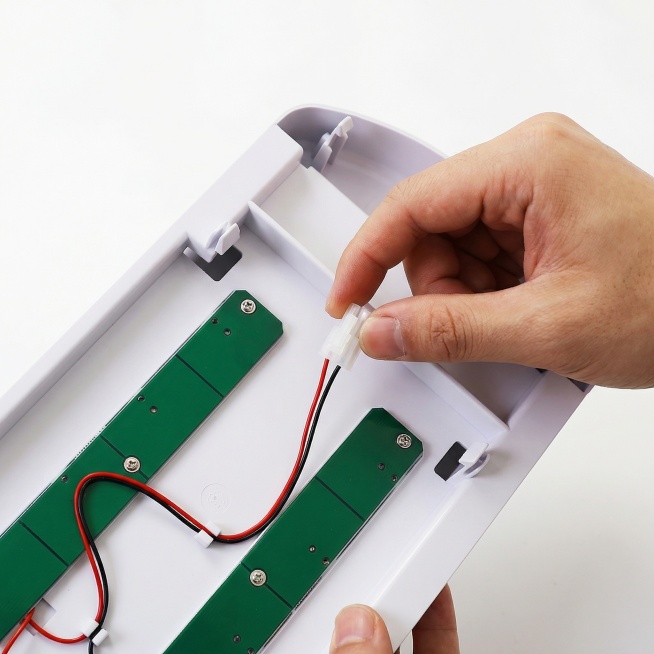 步骤2：一只手正在断开冰箱上拆下的冰箱灯LED灯的白色端子接口，产品维修教程实拍图，清晰写实风格，白色背景预览效果