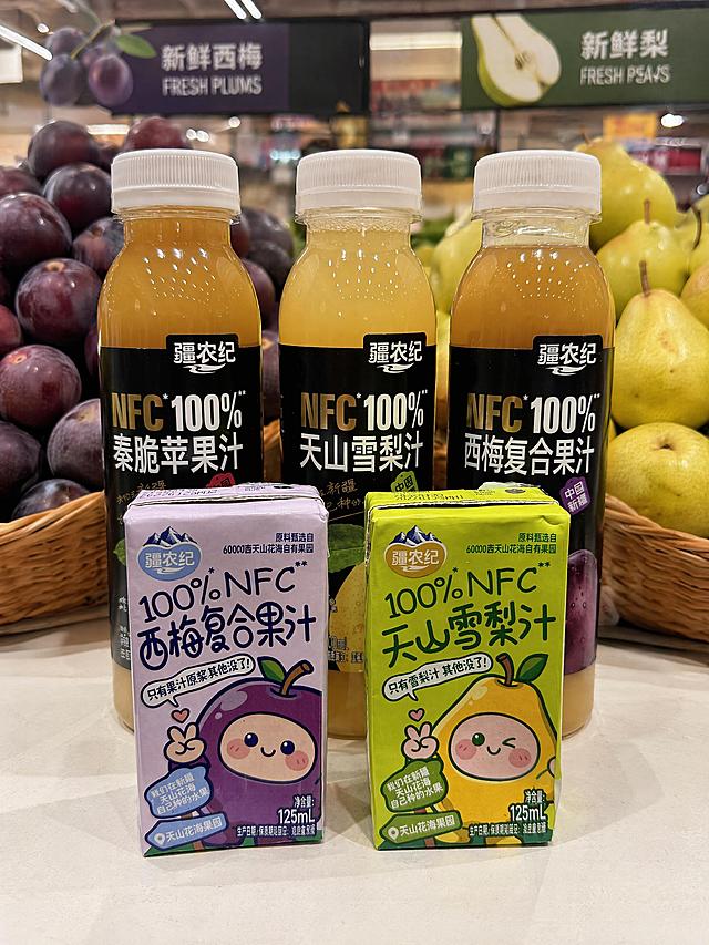 将原图背景替换为超市水果区新鲜西梅和梨背景，保留产品形状、颜色、包装文字和陈列方式完全不变，产品为果汁饮料，瓶身和包装盒完整保留所有文字与图案，自然融入场景光影，与场景共处同一物理空间，构图保持产品位于画面中心，光线明亮柔和，风格写实，严格锁定宽高比为3:4