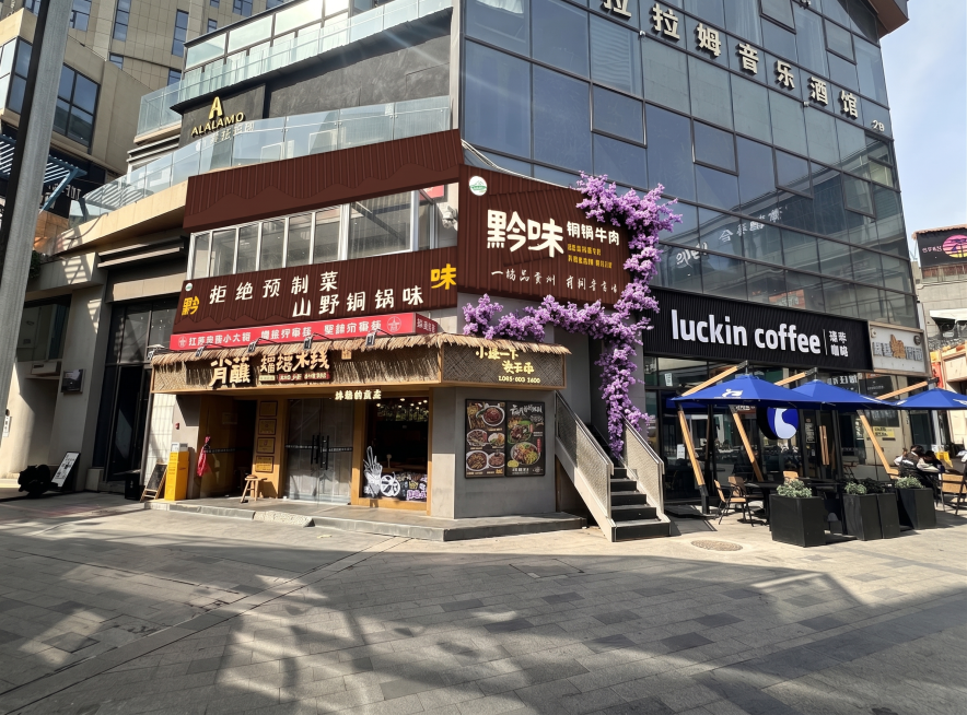 参考图1样式，去掉图2红框内的紫色花，保留原图其他位置的紫色花，去掉右下角水印，其余建筑、招牌、街道等所有内容保留不变预览效果