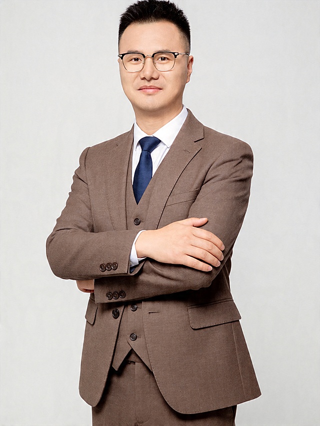 参考第一张图保留人物脸型､发型､年龄等特征生成职场形象照,参考第二张图人物占位和比例,标准焦段50mm,f/4光圈(f/2.8-f/4区间),平视视角(镜头与人物视线齐平);人物占画面70%,人物居中(居中构图),位于画面中心,为视觉聚焦点,入境范围头部及以下至臀部下方10cm(半身像);左右留少量背景空间;头部与画面顶部保留5%空间;头部发型完整,头肩比例协调,整体色调提亮;外搭咖色羊毛混纺平驳领单排扣西装外套,单颗纽扣扣合,袖口四颗同色纽扣,左右带贴袋,修身版型,细腻斜纹肌理,挺括垂坠,内搭同色系咖色西装马甲,修身版型,细腻斜纹肌理,挺括垂坠,内搭纯白色高支纯棉尖领正装衬衫,领口挺括贴合颈部,平整顺滑,搭配同色咖色下装西裤,搭配藏蓝色领带,领带为标准版商务领带,四手结系法,结型饱满端正,面料为哑光梭织,垂感自然｡身体正面完全朝向镜头,双臂交叉抱于胸前,右手轻搭于左臂上,肩部自然放松,姿态舒展优雅,肩部自然放平,姿态端正挺拔,眼神明亮坚定直视镜头,表情沉稳端正,嘴角微扬呈内敛浅笑,展现干练､沉稳､专业的职场气质;发丝整齐服帖,面部干净清爽,无明显妆容,肤色均匀偏暖,呈现细腻哑光质感,T 区微泛健康油光,侧光下鼻梁与颧骨处有轻微高光背景为浅灰色纯色背景,突出人物主体,背景轻微虚化;肤质呈现匀净哑光质感(自然白皙);轻透裸妆+重点提亮;唇色透亮润泽(半哑光质地);背景光线均匀,明暗过渡柔和,强化色彩对比的高级感｡极简干净打光采用柔光主光(5200K中性白光,柔化面部光影,突出面部轮廓立体感)+补充暗部细节,避免过曝),整体光线均匀柔和,明暗过渡自然;画质为超高清精细质感,中度锐化,画面纯净无噪点,严格按照原图内容生成｡