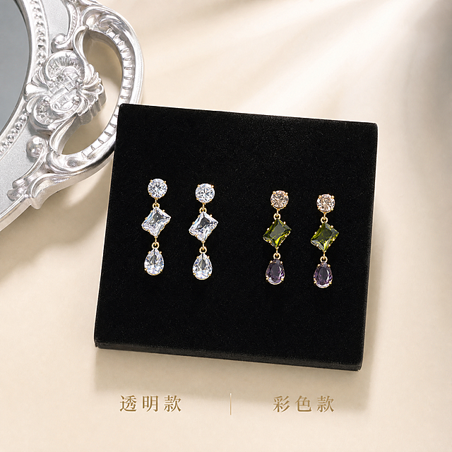 [主图-4 重制] 两款耳环对比陈列，严格保持原图耳环款式和细节不变。
[统一基调] 精致轻奢珠宝风格，柔光箱高光+窄条轮廓光，奶油白浅色系背景，整体高透光微距质感。
[画面] 黑色丝绒展示垫上，左右并排摆放两对耳环。左侧透明款：金色耳针+圆形透明锆石+菱形透明锆石+水滴形透明锆石，三层结构。右侧彩色款：金色耳针+圆形香槟粉锆石+菱形橄榄绿锆石+水滴形深紫锆石，三层结构。两对耳环款式细节严格与参考图一致，对称摆放。左上角银色复古镜框一角装饰。背景奶油白渐变。俯视微倾斜角度。
[光影质感] 商业珠宝摄影质感，柔光箱顶光+侧光，宝石切面丰富高光火彩，金属轮廓光清晰，丝绒质感细腻。
[配色] 奶油白背景，黑色丝绒，金色金属，透明款淡蓝光晕，彩色款三色鲜艳。
[文字版式] 底部中央细衬线字，左"透明款"右"彩色款"，浅金色。
[输出要求] 1:1正方形，2048x2048像素，两对耳环款式细节均与参考图完全一致，不变形不改变结构。负向：耳环款式改变、宝石形状错误、结构变形、不对称、画面杂乱。