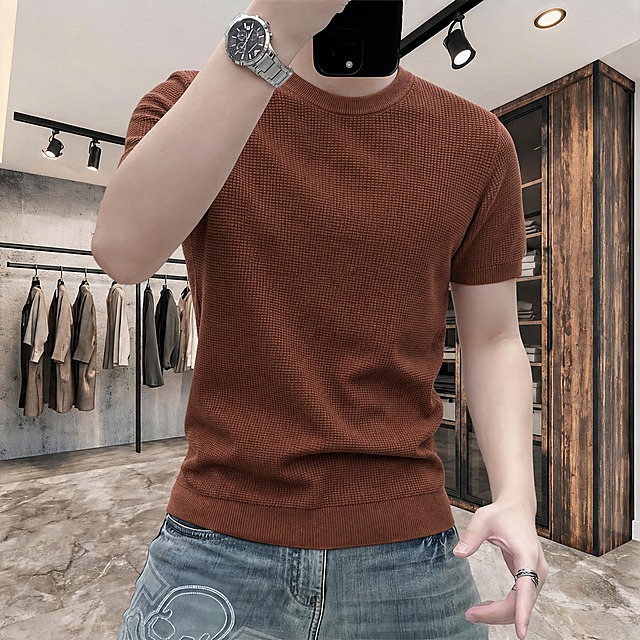 将第一张图中模特身上的白色短袖上衣，替换为第二张图中的棕色华夫格针织圆领短袖上衣。严格保留第二张衣服的原始颜色，不允许有任何颜色变化。衣服的圆领、短袖袖口、华夫格纹理、针织条纹细节必须100%还原呈现。面料褶皱随光影产生自然明暗层次，避免大面积死黑阴影，体现服装立体质感、写实面料光影、商业男装专业布光效果。模特的皮肤光影、牛仔裤光影完全保持不变。背景完全保留第一张原图的服装店场景原样，不做任何改动。整体超写实风格，极致面料细节，高清质感，服装电商摄影级别，画质锐利，无损画质。