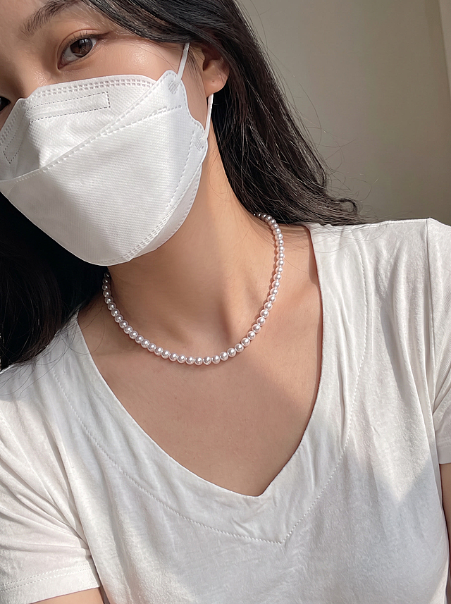 【主体保护指令】请保持参考图 1 中的【同一模特、同一服装、同一场景光感】一致，包括面部五官、脸型、发型、白色V领上衣款式与颜色、珍珠项链商品原貌与结构、背景色调、自然光光影，不做改动。仅姿势、镜头景别、朝向按描述重新生成。

画面整体为日常穿搭展示图，模特回眸看向镜头，肩颈微侧，颈部近景特写，侧面回眸朝向，常规机位，自然构图。

人物与参考图1保持一致，不做改动。

服装与珍珠项链商品以参考图1为准，商品原貌与结构不变。

背景与参考图1保持一致。

光影与参考图1保持一致，自然光感。

画质与参考图1保持一致。

整体为日常自然光人像风格，清新自然，简约真实。

近景特写景别，中焦镜头，微侧机位，项链位于画面视觉中心，突出珍珠光泽与V领领口搭配效果。

画面与参考图 1 在模特面部、服装、背景、光影、色调上保持高度一致；人物特征稳定（五官 / 肤色 / 发型一致）；服装细节准确；珍珠项链商品结构不变；关节合理、姿势自然。