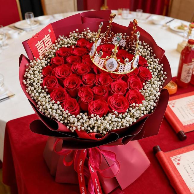 在这束红玫瑰花束的玫瑰花外圈添加一圈白色满天星装饰，保留花束原有的红色包装、金色皇冠和喜字装饰，整体风格保持不变预览效果