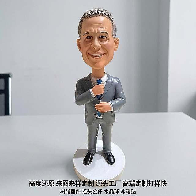 [垫图] https://gdesign-dam-hz.dancf.com/35908963866887286/c9240937dc3c432aa9acfcb0e87dbb31.jpg
[主图主题] 单人西装名人公仔电商主图
[氛围/风格] 明亮清晰商务办公风格，超高清写实，质感细腻，背景简约办公风
[画面元素] 单人西装名人公仔摆件放置在平整浅灰色办公桌面上，保留原图产品造型、颜色、比例和正面角度完全不变，背景替换为纯净简约的办公室浅灰色墙面背景，产品主体完整居中展示，占据画面约60%区域，柔和自然光突出树脂纹理和立体轮廓，背景干净无任何多余杂物
[配色色系] 主色：产品自身灰色 棕色 黑色；辅助色：浅灰色办公桌面，浅灰色办公背景，色彩商务协调
[视角构图] 完全保留原图正面拍摄角度，景深适中，主体清晰突出，边缘完整不切割
[文字版式] 图片底部桌面区域居中放置文字，第一行黑色文字"高度还原 来图来样定制 源头工厂 高端定制打样快"，第二行黑色文字"树脂摆件 摇头公仔 水晶球 冰箱贴"，字体大小对比清晰，文字分行居中排列，完全不遮挡产品主体，四周保留充足安全边距，整体构图平衡舒适，符合国内电商主图规范。