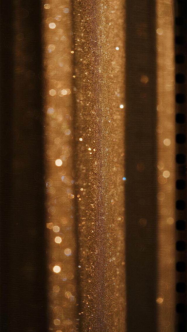 温暖的胶片风格摄影作品，画面呈现深棕色与金色交织的复古色调，背景中垂直排列的模糊光影形成自然的光柱效果，弥漫着大量细碎的光斑和颗粒感，营造出梦幻而怀旧的氛围，胶片特有的颗粒质感和轻微的光晕效果显著，整体画面朦胧而富有层次感，暗部细节丰富，高光区域呈现柔和的扩散状，没有明显的锐利边缘，充满复古电影感的视觉效果。