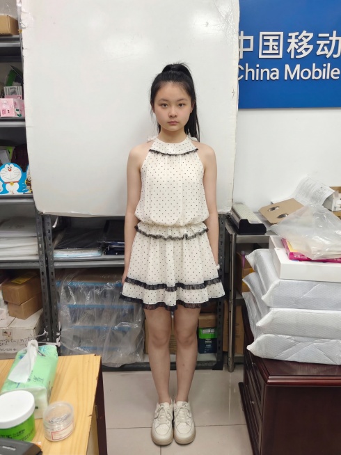 给图1中的人物换上图2的波点挂脖连衣裙，去掉灰色长裤，补充完整服装细节，保留人物原本的五官和姿态预览效果
